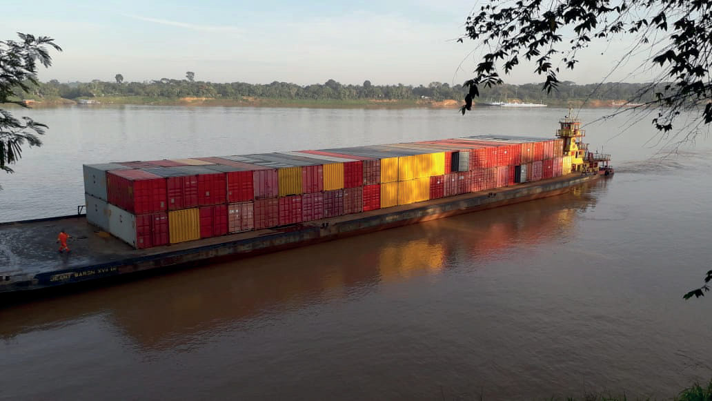 Balsa carregada de contêineres navegando em rio da Amazônia
